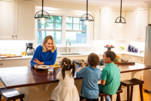 Family gathered at a kitchen island in a bright, well-designed home, reflecting everyday living and the shift toward comfortable, functional spaces that support modern lifestyles