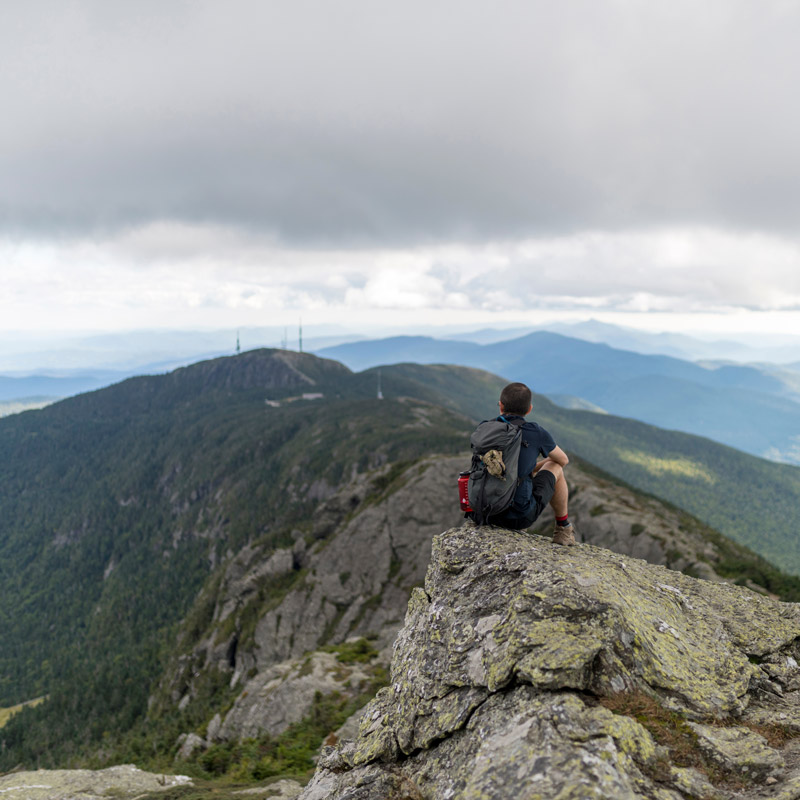 Man looking out over the Green Mountains from the top of Mount Mansield
