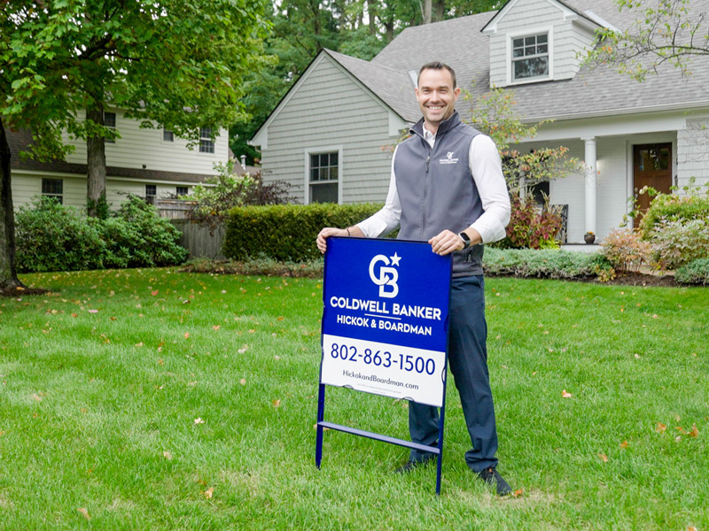 John Black, an Agent, stand sin front Coldwell Banker Hickok & Boardman Sign